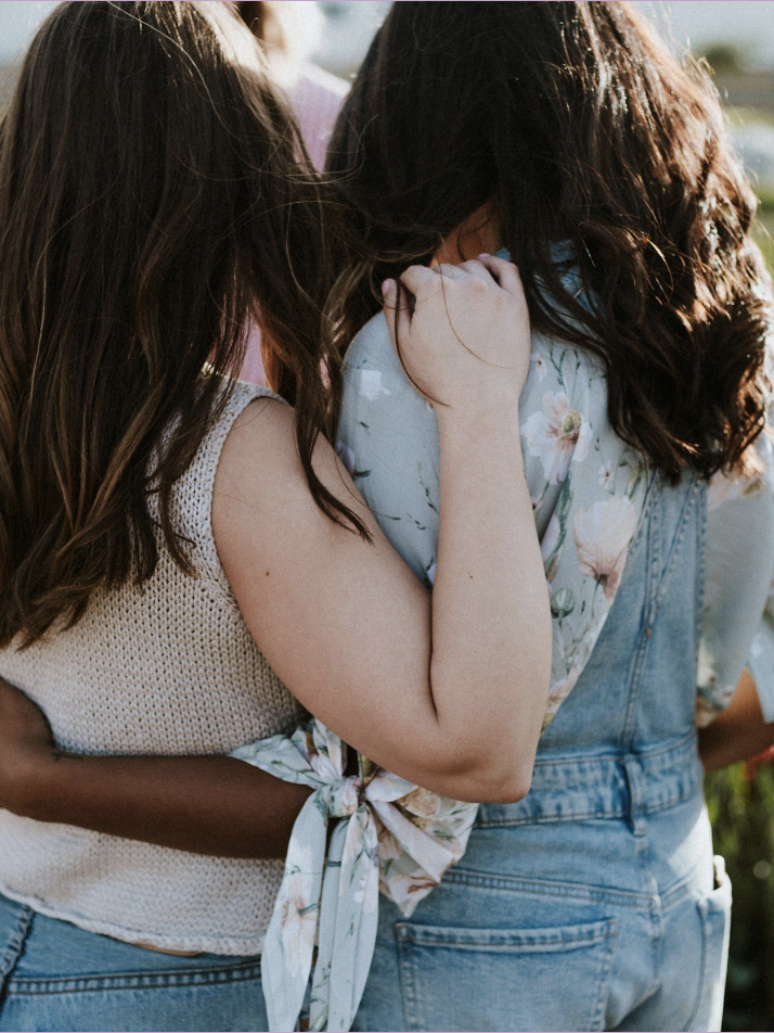photo of two woman hugging from behind