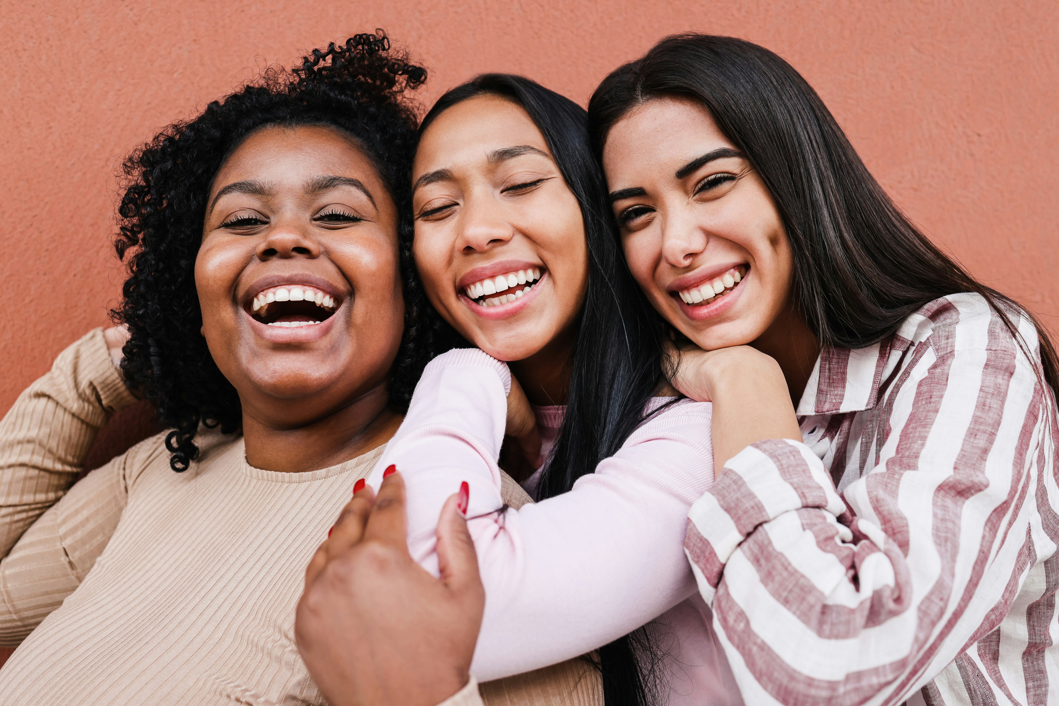 A photo of three women laughing and looking into the camera